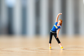 Tiny figurine of a woman in athletic wear performing a side stretch