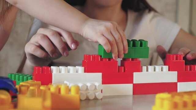 child play constructor with mother. red white colors. parent build together with kid from toy lego brick. teamwork. psychologist deals with child. happy family. group game constructor. chidhood dream.
