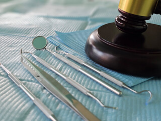 Dental instruments and gavel on a surgical drape in a clinical setting for a legal discussion