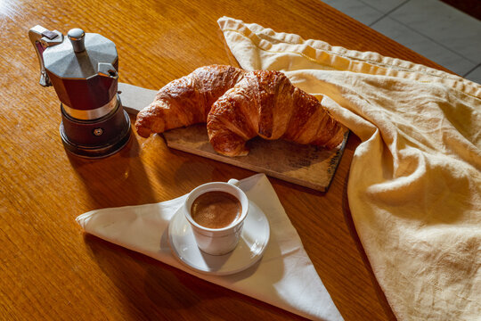 Top view of a coffee cup with cornetti and wooden table at sunset