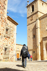 Pilgrims on the Camino de Santiago crossing the historic center of Cáceres, Extremadura, Spain. Pilgrims walking in front of the Cáceres Cathedral on the Via de la Plata.