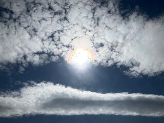 Blue sunny sky with Stratocumulus volutus, Roll clouds and pearl colors, optical phenomenon Iridescence on Altocumulus around sun. Topics: weather, meteorology, nature, airspace