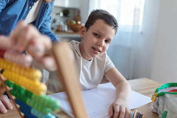 Learning math, father and kid writing in book in home studying, homework help or homeschool tutor. Happy dad, boy and teaching in education, mathematics and knowledge for child development in house.