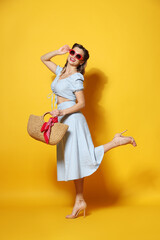 Happy pin-up woman in sunglasses posing with bag on orange background