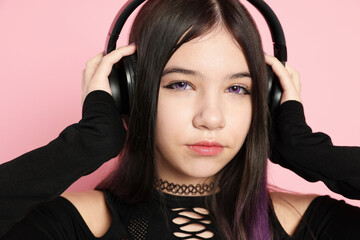 Teenage girl with headphones posing on pink background. Makeup and clothes in anime style