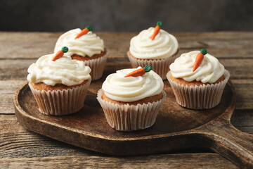Delicious carrot cupcakes on wooden table against grey background, closeup