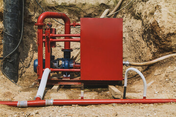 Industrial water pump with red pipes and control box installed on a construction site