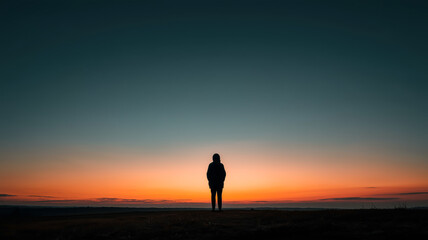 Silhouette against a fiery sunset, creating a poignant and contemplative moment of solitude and connection with nature. 