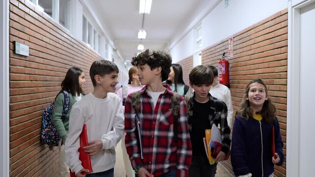 Elementary school students walking together in school hallway, carrying books, chatting animatedly with classmates during break time, showcasing friendship and youthful energy