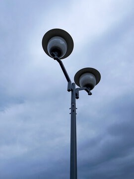 Fototapeta minimalist photo of modern street lamp with two globe-shaped lights, set against an overcast sky, emphasizes the simplicity and functionality of urban design