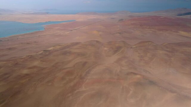 Aerial View of Ocean and Desert Coastline at Paracas National Reserve, Peru. This stunning aerial footage captures the breathtaking contrast between the deep blue Pacific Ocean and the arid desert 