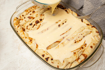 Pouring sour cream sauce on a cheese  pancake pie , preparation process