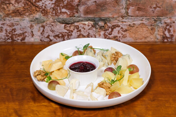 Plate with grapes, nuts, microgreens and sauce. Sliced ​​food for wine. Catering. Restaurant food. Serving dishes