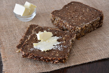 slices of Bread with butter on a rustic wooden table with burlap texture