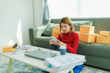 A young woman is starting her SME business, checking information and preparing packages to be...