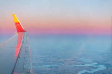 Wing view of aircraft flying in the evening time. Belt of Venus in the background © Dushlik