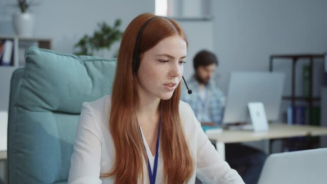 A woman with a headset sits at her desk engaged in a virtual meeting