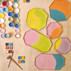 top view of handmade clay plates covered with colored glazes and glaze jars, ready for firing