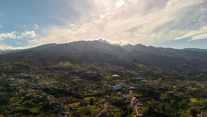 Majestic mountain landscape under a brilliant sky with lush greenery and scattered villages in the distance at midday