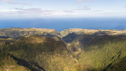 Majestic landscape view over lush green valleys leading to the shimmering blue ocean in a serene morning light