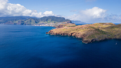 Vast ocean meets dramatic cliffs along the coastline of a picturesque island bordered by vibrant hues of blue and green