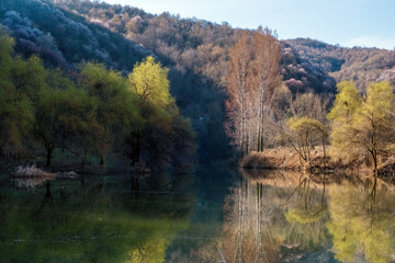 A beautiful small lake surrounded by trees with fresh spring foliage and blooming gardens. Almaty, Kazakhstan
