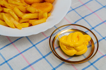 French fries and golden nuggets with cheese sauce on tablecloth fragment