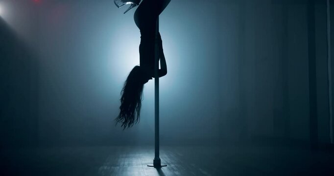 Woman, exotic dancing and pole with spin, stage and creativity with balance for concert event in dark. Person, dancer and movement with swivel, performance and flexible for fantasy at nightclub