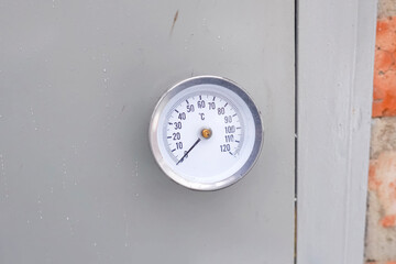 High temperature thermometer on gray door of the room.
