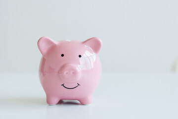 Small pink piggy bank smiling on a white surface ideal for saving money and financial education