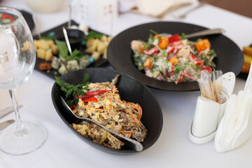 Variety of delicious cold snacks are served on black ceramic plates at the wedding banquet.