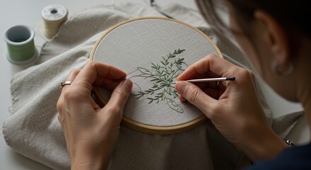 Woman embroidering green floral design onto fabric with embroidery hoop