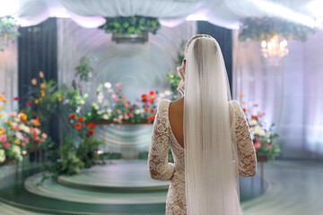 Elegant bride in a wedding dress against a background decorated with vibrant flowers before ceremony