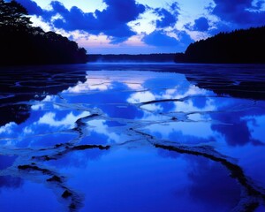 Lake reflects twilight sky between forest shores; tranquil water, atmospheric light, clouds