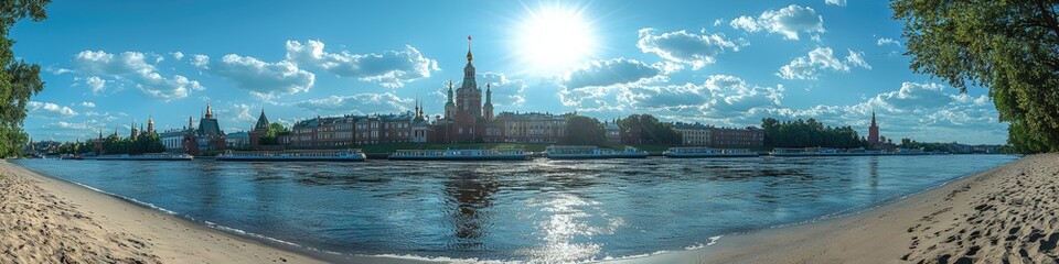 Obraz premium Panoramic view of a riverfront cityscape under a bright sunny sky. Sandy beach in foreground