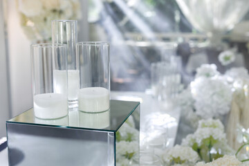 Wedding decorations made of white flowers and candles in close-up on table of the bride and groom.