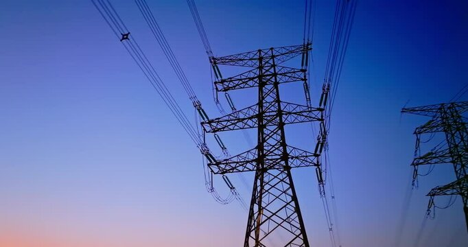Aerial view perspective looking up at high voltage electricity pylons and power lines against a deep blue twilight sky