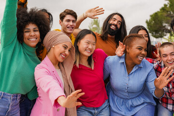 Multiracial young people waving hands in front of camera - Happy diverse friends having fun outdoor...