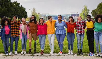 Obraz premium Group of multiracial friends hugging each other while walking in the city - Young people outdoor during spring season - International and diverse culture concept