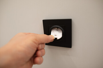 Safety cover is inserted into outlet, indicating a precaution intended to protect children from electrical hazards.Hand placed safety cover over an electrical outlet.Safety plugs,prevent child hazard.