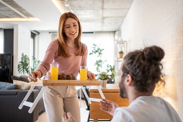 Woman bringing breakfast in bed to her husband