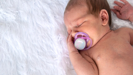 baby sleeping with a pacifier on a light background. pacifier,habit.