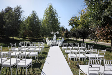 An arch for a wedding exit ceremony with white flowers, a path and crystal chandeliers.