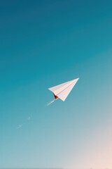 isolated single paper airplane soaring upward in clear blue sky represents reaching career aspirations