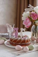 Table setting with traditional easter cakes with icing decorated with gingerbread cookies in shape of rabbits on white wooden table
