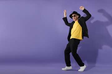 Stylish man dancing on violet background. Space for text