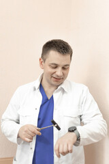 The doctor is holding a reflex nerve tapping instrument and looking at the watch