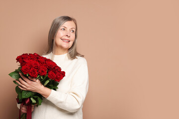 Smiling woman with bouquet of roses on beige background. Space for text