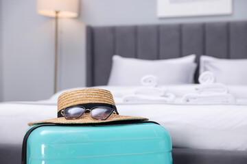 Fototapeta premium Suitcase with hat and sunglasses in hotel room, closeup