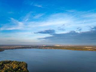 Colorful autumn forest with trees on the shore of a blue lake - top aerial view.